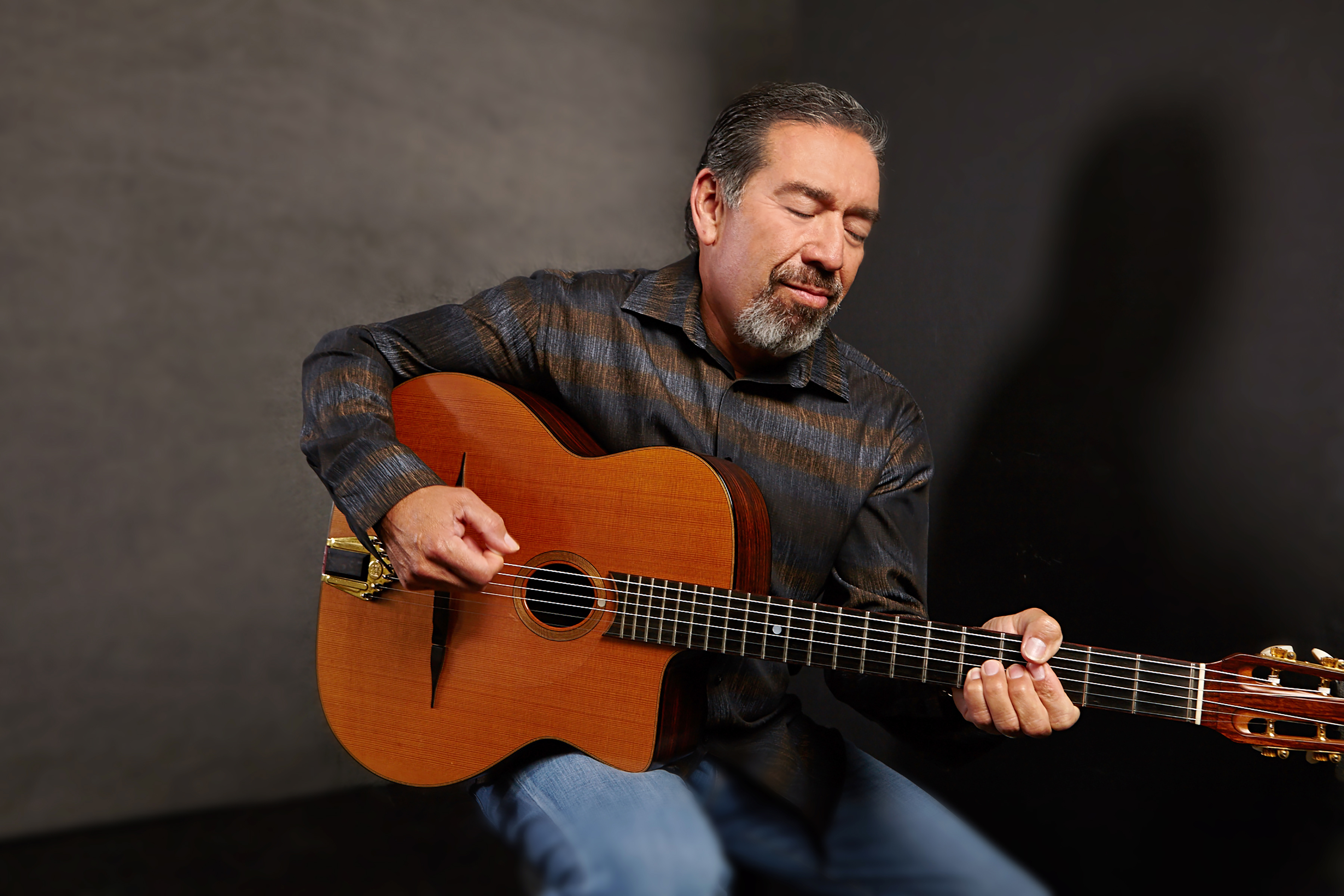 Guy Gonzales holding a guitar looking down